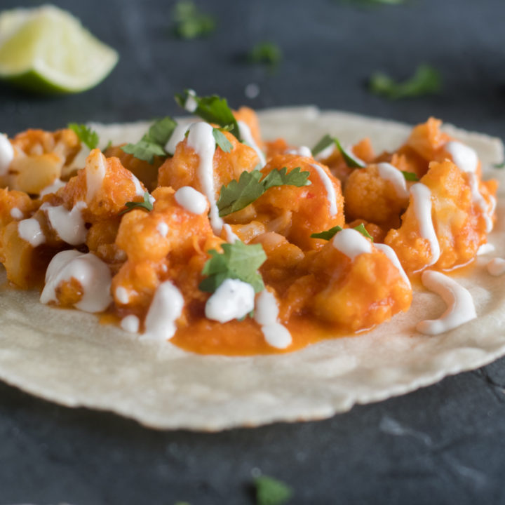 Spicy Cauliflower and White Beans Tacos topped with a cashew crema. These tacos get a spicy kick from dried chiles!