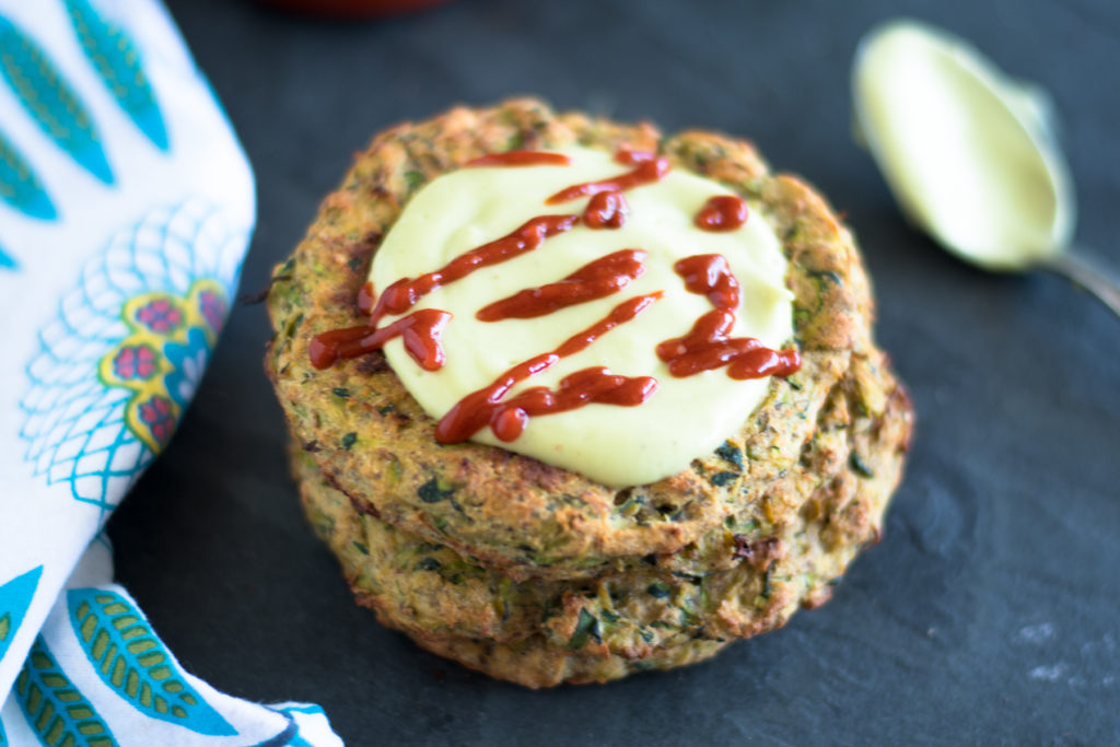 Vegan Zucchini Fritters topped with an avocado crema and sriracha! Perfect for an appetizer or light dinner.  #vegan #appetizer #zucchini #summer #recipes #glutenfree #fritters #vegetarian 