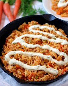 This Vegan Buffalo Chicken Rice Skillet is perfect for a weeknight dinner. Vegan chick’n, brown rice and veggies are smothered in hot sauce and topped with ranch sauce for a tasty meal!
