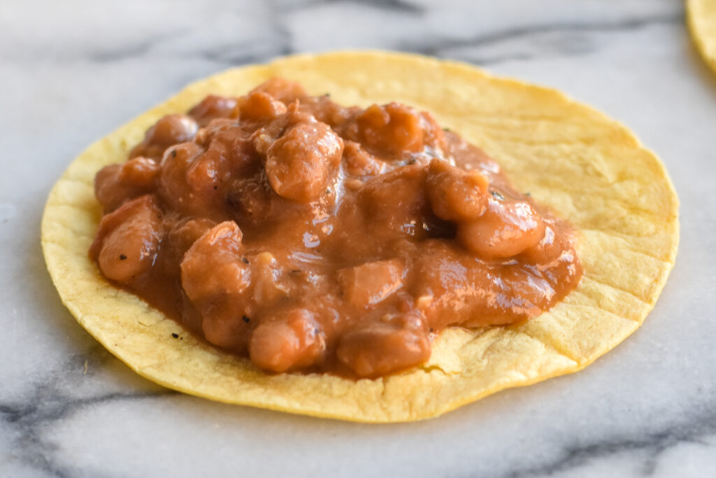 This Mexican bean recipe for tacos starts with chile infused pinto beans served in a warm corn tortilla topped with an easy, light refreshing slaw. 