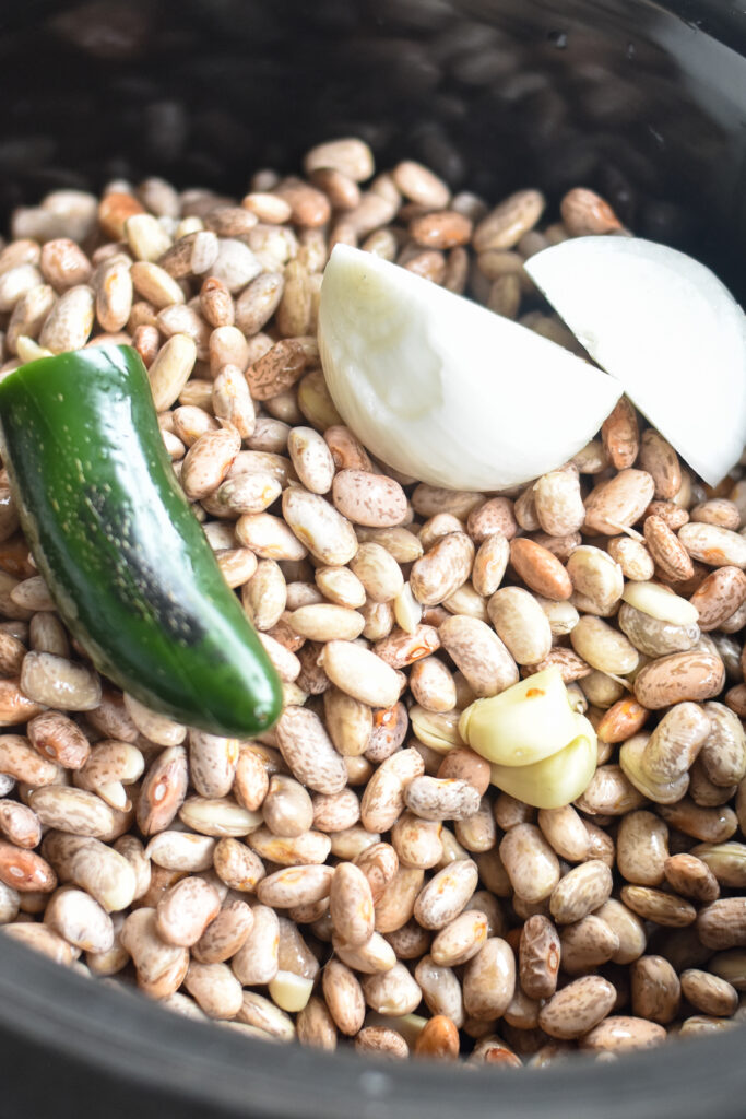 Pinto beans are cooked with white onion, garlic and a jalapeño. As the pinto beans cook in the slow cooker, the absorb all the flavors from the onion, garlic and jalapeño. 