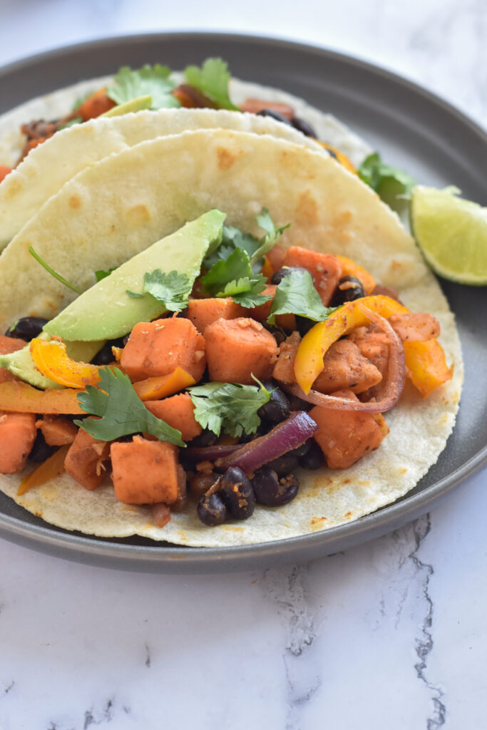 Quick, easy vegan sweet potato and black bean tacos topped with cilantro, avocado and fresh lime. 
