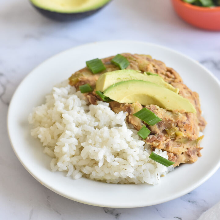 Budget-friendly plant-based dinner recipe featuring canned pinto beans cooked with green chiles served over white rice.